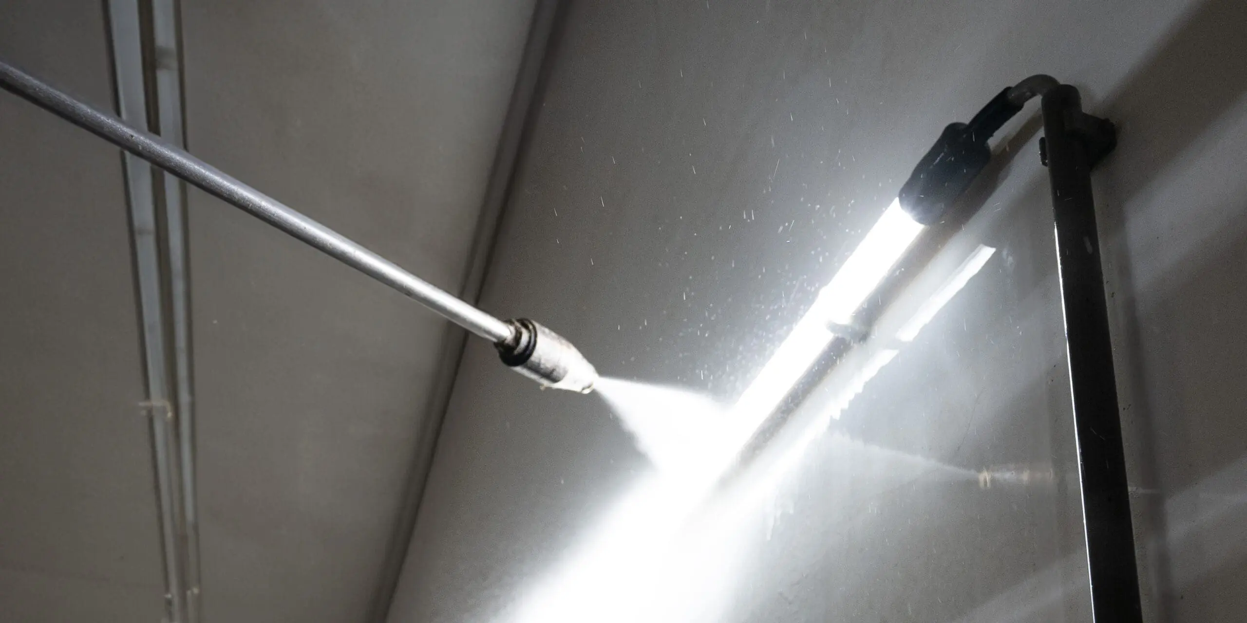Tlakový čistič mířený na LED svítidlo v prasečí stáji